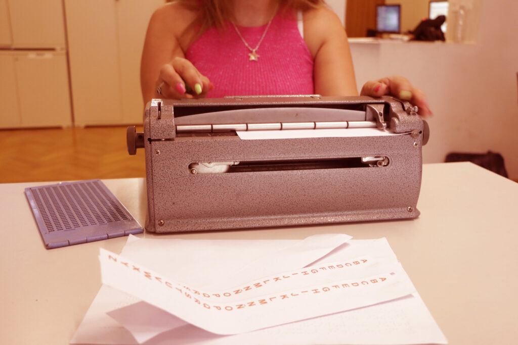 Personal municipal especializado del Servicio escribiendo con una máquina de escribir braille.