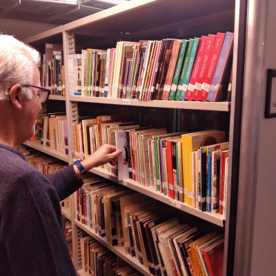 Foto de personal y de la estantería de la Biblioteca de autores rosarinos en el depósito de libros de la Biblioteca Argentina.
