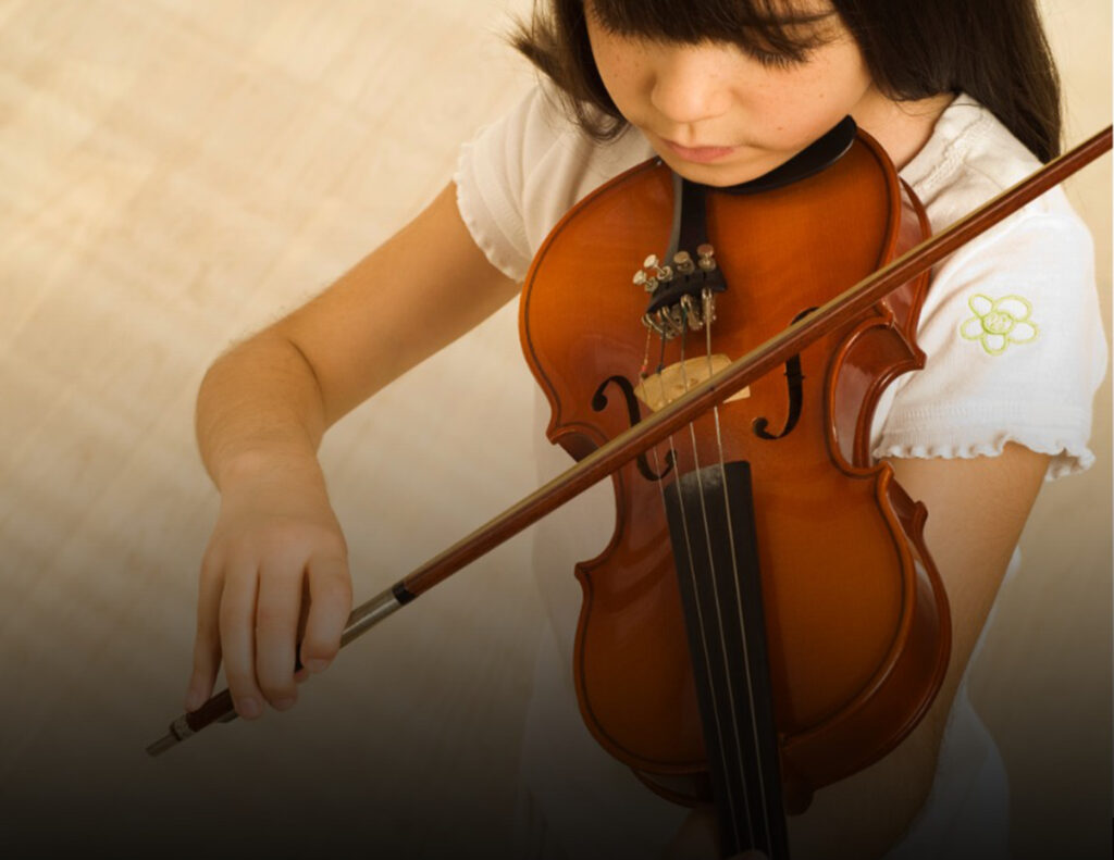Foto de una niña tocando el violín vista desde arriba.